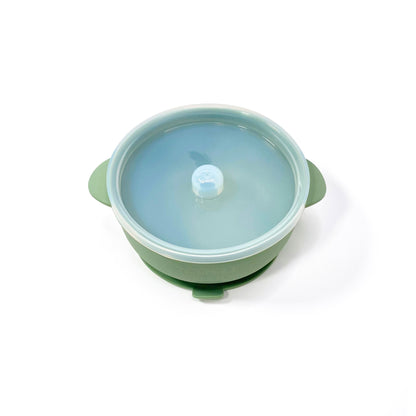 A forest green silicone children’s feeding bowl, with lid and suction cup. Image shows the bowl with lid attached.
