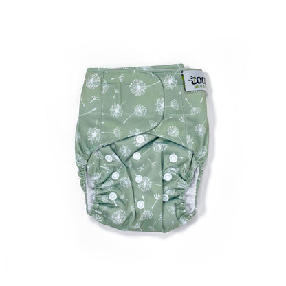 An adjustable reusable nappy for babies and toddlers, featuring a green dandelion design, with images of dandelion seeds on a green background. View shows the front of the nappy, with fastenings closed.