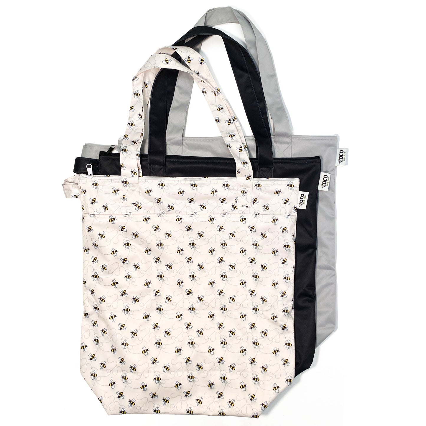 A collection of three zipped tote bags in black, grey and bumble bee designs, made from bamboo fibres in a bumble bee design, featuring two zipped sections and a handy loop tab to easily roll up the bag for storage. Image shows the bags upright with handles showing.