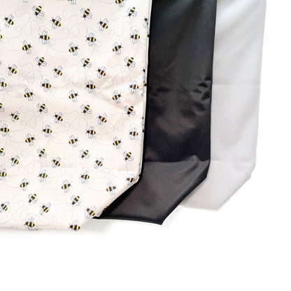 A collection of three zipped tote bags in black, grey and bumble bee designs, made from bamboo fibres in a bumble bee design, featuring two zipped sections and a handy loop tab to easily roll up the bag for storage. Image shows the bags zoomed in, showing the bottom of the bags in greater detail.